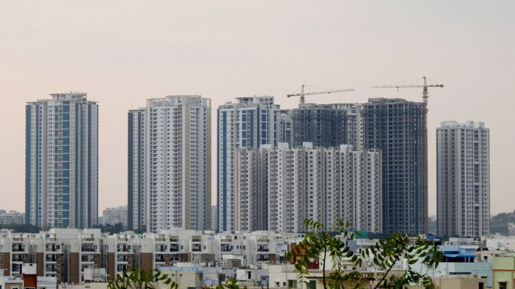 Urban high-rise construction with cranes, representing the group-housing and hotel land now being auctioned by YEIDA near Noida International Airport