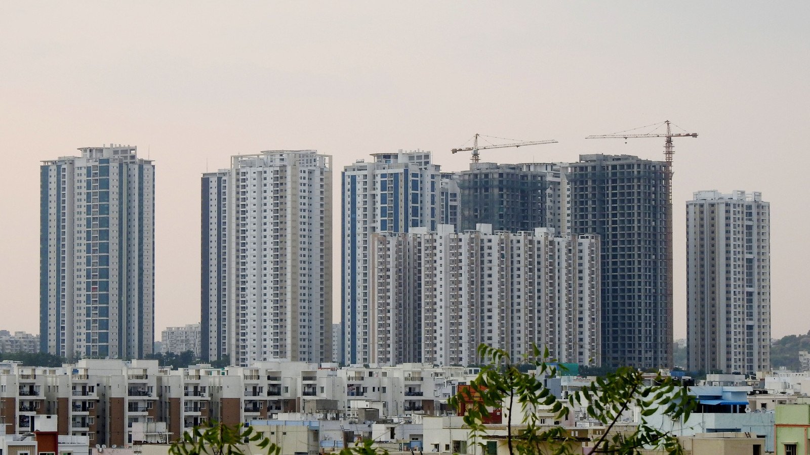 Urban high-rise construction with cranes, representing the group-housing and hotel land now being auctioned by YEIDA near Noida International Airport